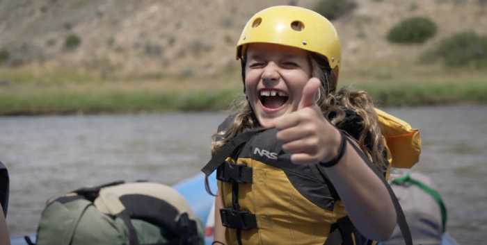 kid thumbs up while rafting